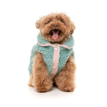 Load image into Gallery viewer, Dog sitting facing forward wearing the FuzzYard Hana Dog Jacket in sage, showing the cosy sherpa fabric and pink trim.