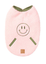 Load image into Gallery viewer, FuzzYard Nara Reversible Dog Jacket in pink sherpa shown flat from the back with embroidered smiley face and contrast olive trim.