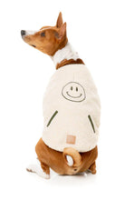 Load image into Gallery viewer, Medium dog turning back while wearing the beige sherpa dog jacket with smiley patch.
