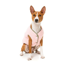 Load image into Gallery viewer, Dog sitting wearing the FuzzYard Nara Reversible Jacket in pink sherpa, showing the embroidered smiley face on the back.
